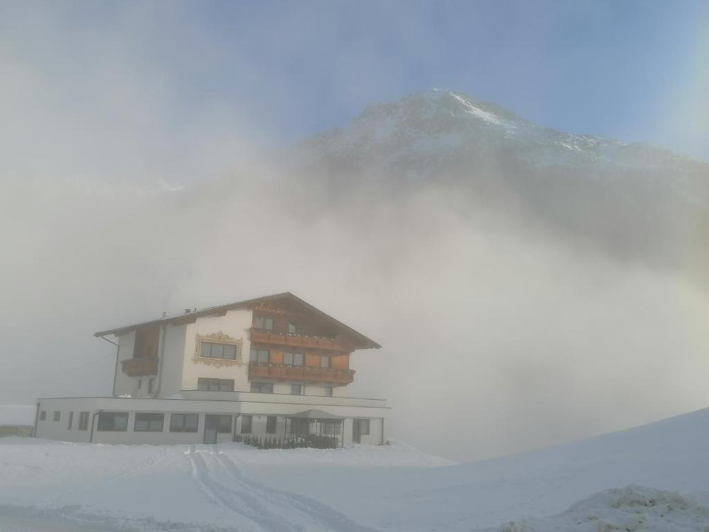 ein Gebäude im Schnee mit einem Berg im Hintergrund in der Unterkunft Appartement Belmonte in Sölden