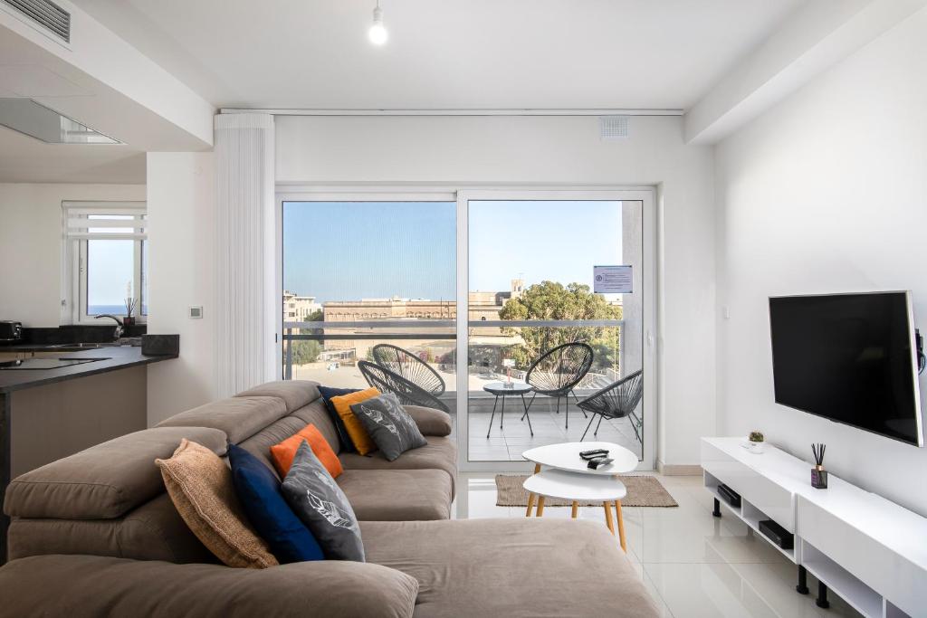 a living room with a couch and a flat screen tv at Spacious, Modern & Cosy 2 Bedroom 2 Bathroom Apartment - St. Julians in St. Julianʼs