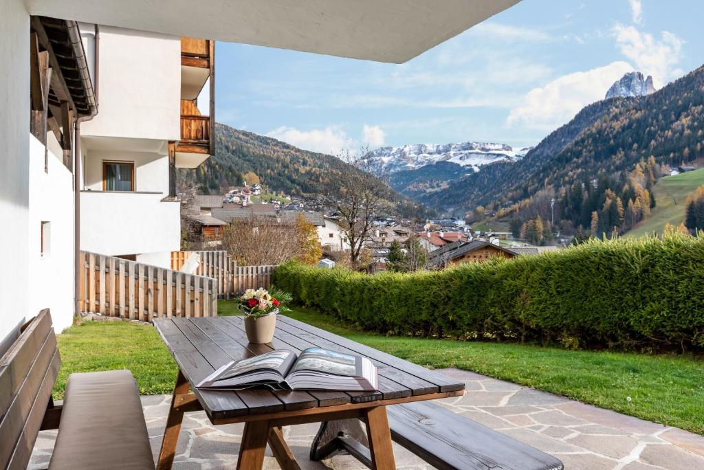 a wooden table with a book on a balcony with mountains at Villa Erina App D2 in Ortisei