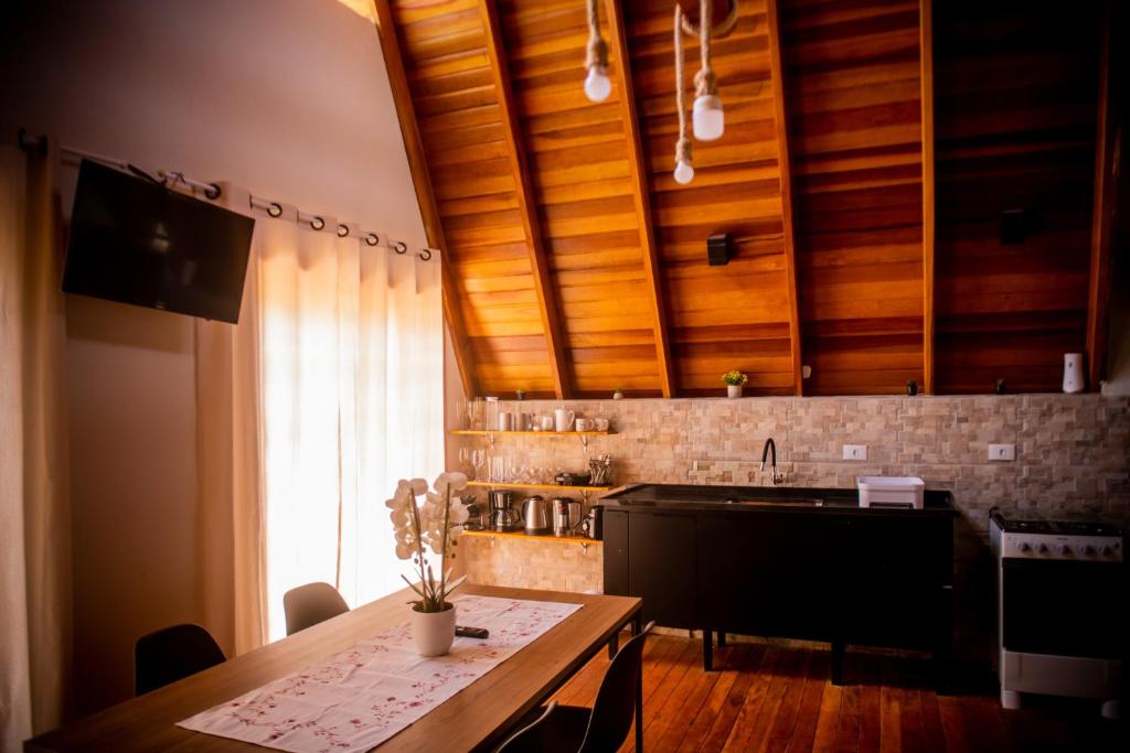 una cocina con techos de madera y una mesa con flores. en Chale em Curitiba - Chales Portugal, en Campo Magro