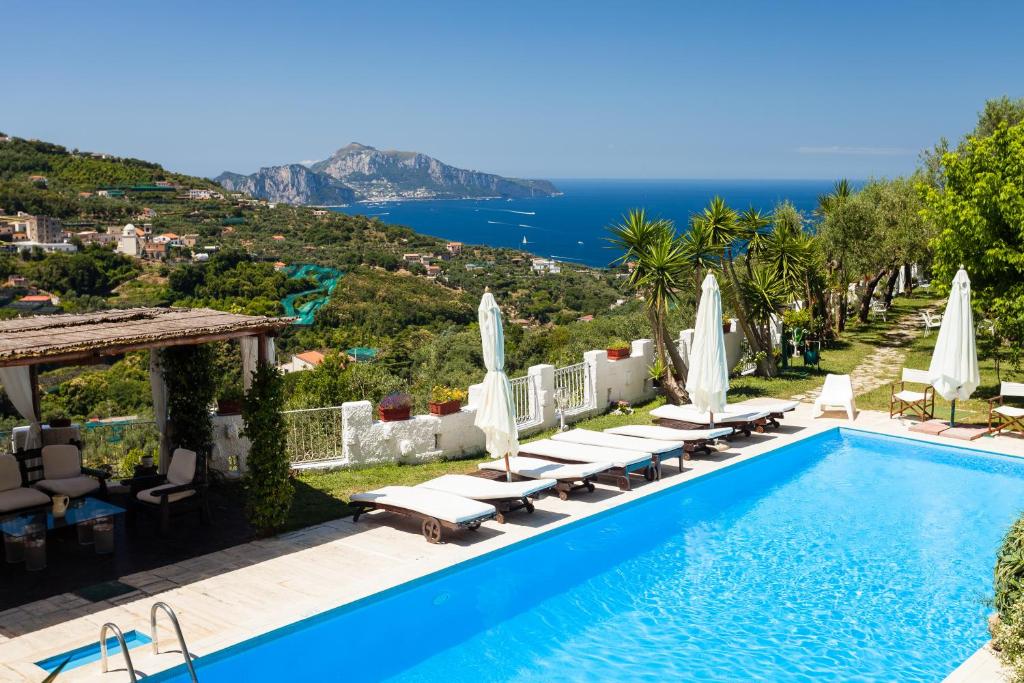 a swimming pool with lounge chairs and umbrellas at Villa Sole di Capri - Vista Mare in Massa Lubrense