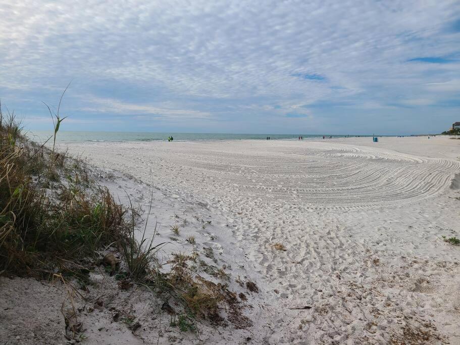 a sandy beach with people in the ocean on a cloudy day at Beachside Retreat W Heated Pool in St. Pete Beach