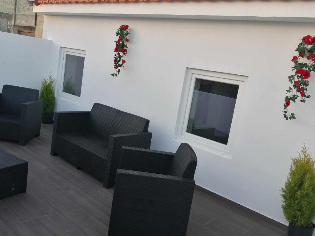 a patio with black chairs and a tv on a white wall at Casa de Praia Daniel in Lavra