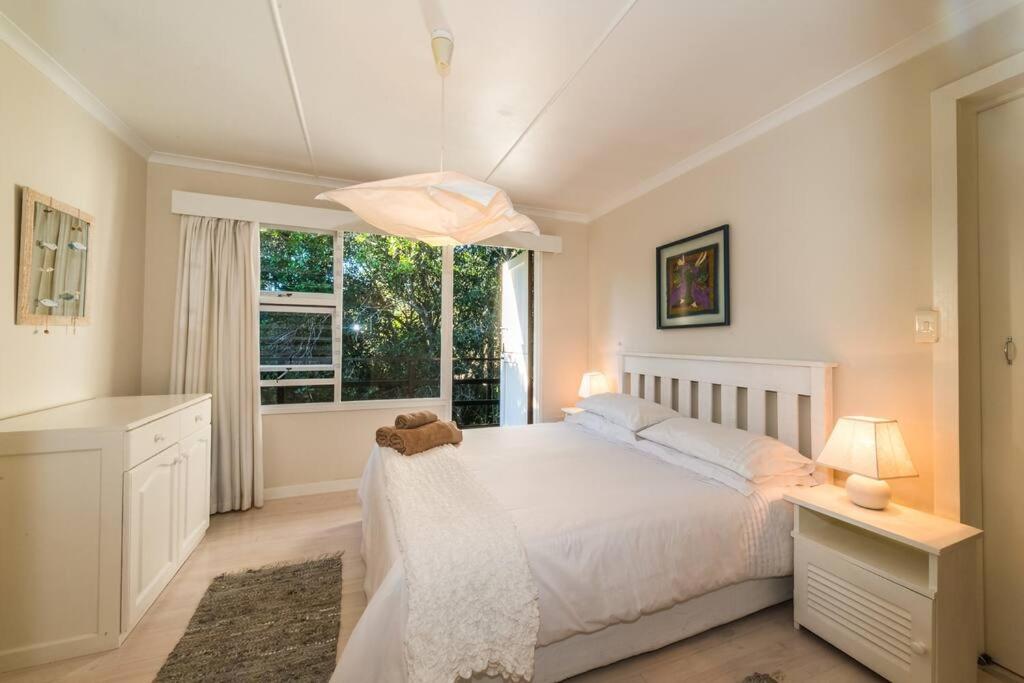 a bedroom with a white bed and a window at Kostaplenti in Natureʼs Valley