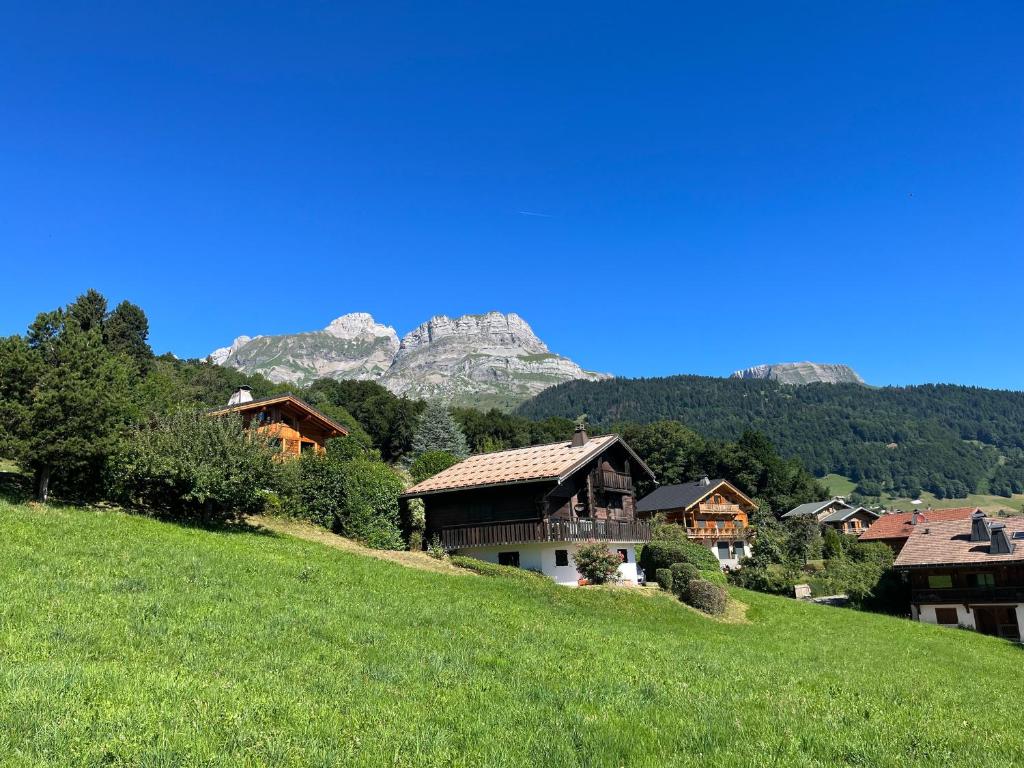 eine Gruppe von Häusern auf einem Hügel mit einem Berg im Hintergrund in der Unterkunft Chalet à Cordon face à la chaîne du Mont Blanc in Cordon