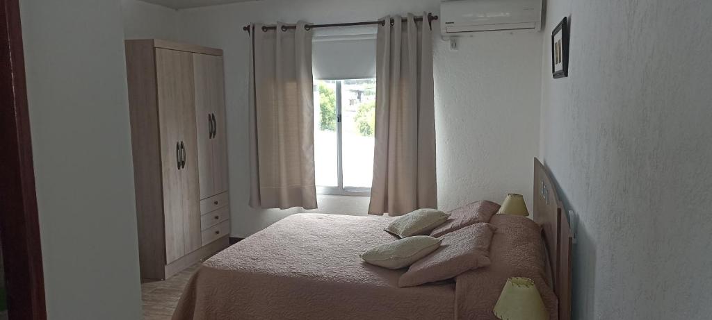 1 dormitorio con cama con almohadas y ventana en Hosteling Las Margaritas, en Minas