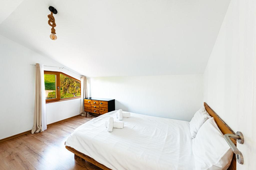 a white bedroom with a bed and a window at Le Chalet M - Cabană cu o panoramă de poveste. in Şurdeşti