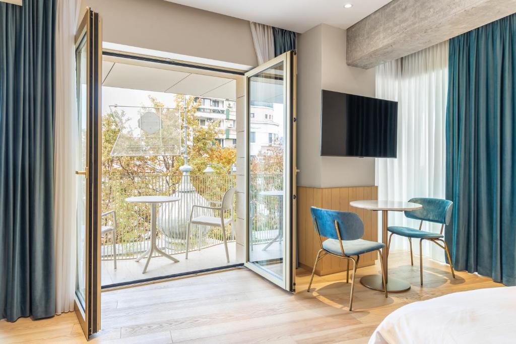 Habitación con cama y balcón con mesa y sillas. en Rosetti Hotel en Bucarest