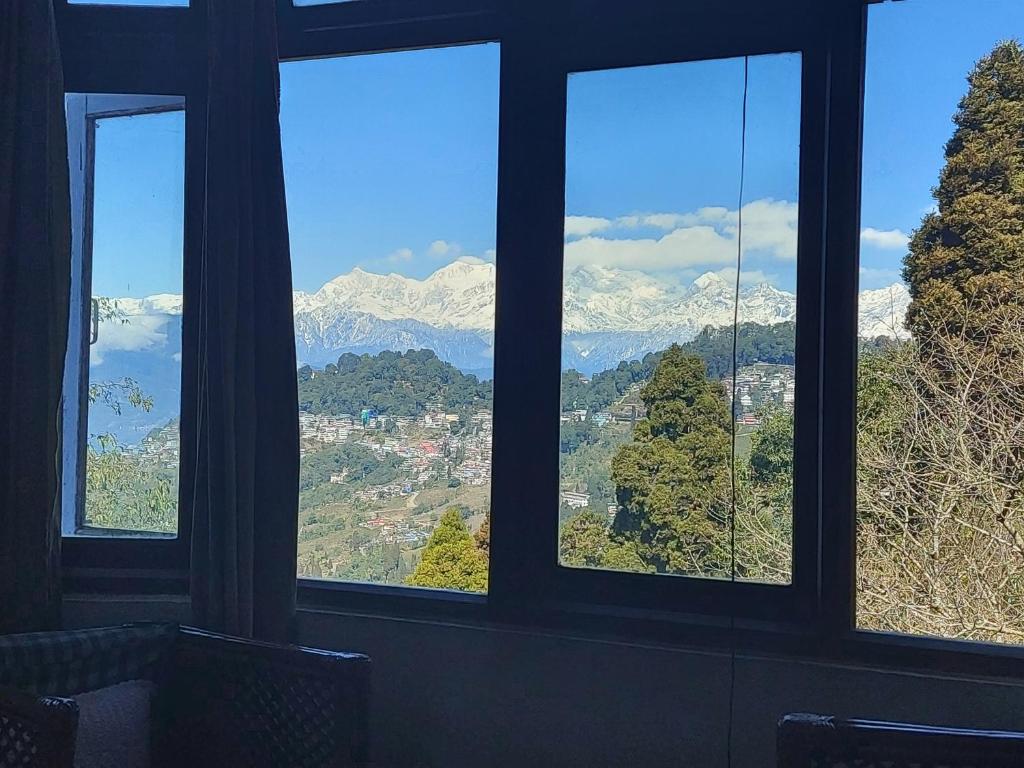 a room with four windows with snow capped mountains at Hotel Sakura in Darjeeling