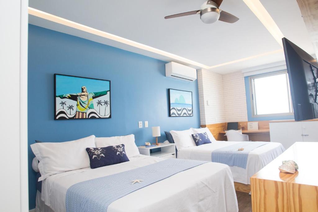 Hotel Barra da Tijuca de frente para o mar - 2 suítes até 6 pessoas em camas, a bedroom with two beds and a blue wall at Barra da Tijuca de frente para o mar - 2 suítes até 6 pessoas em camas in Rio de Janeiro