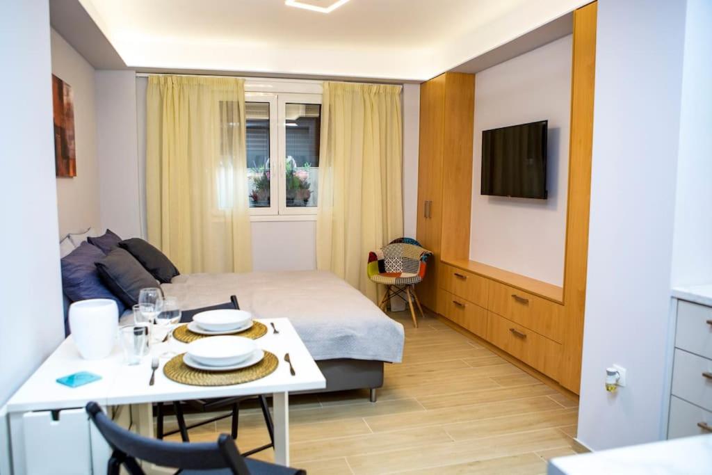um quarto de hotel com uma cama e uma mesa e uma televisão em Studio apartment with all amenities in Kolonaki em Atenas