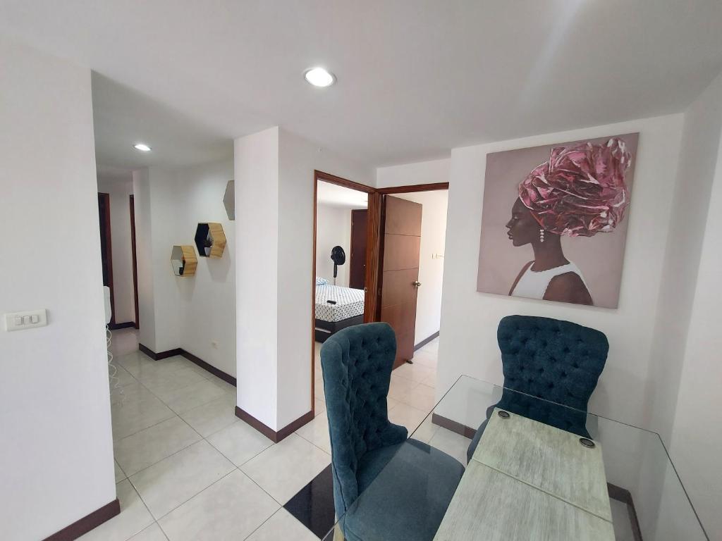 una sala de estar con 2 sillas y una pintura en la pared en Apartamento Laureles la 33, en Medellín