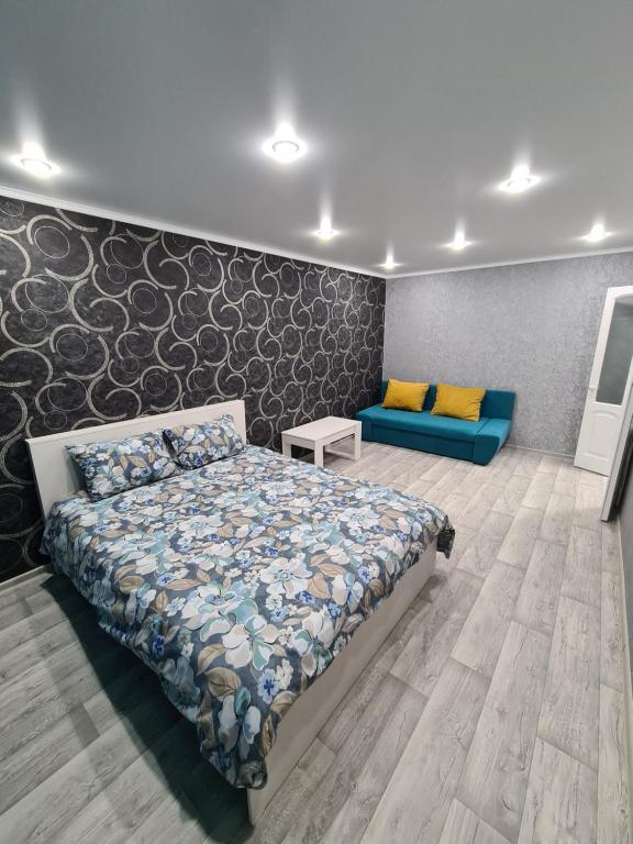 1 dormitorio con 1 cama y 1 sofá azul en Однокомнатная квартира в центре Петропавловска, en Petropavlovsk