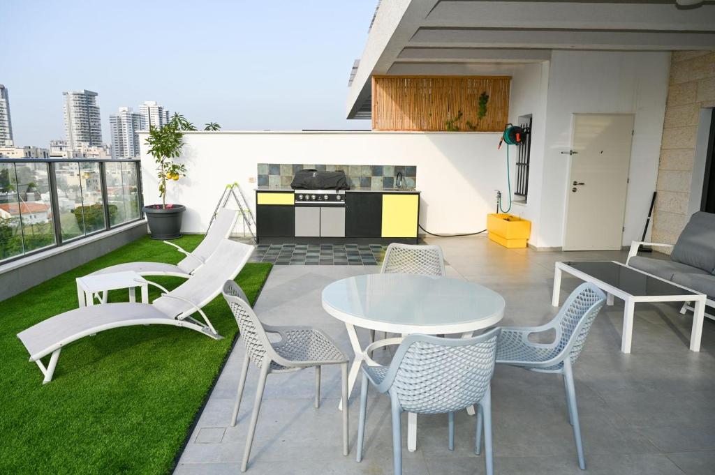 a patio with a table and chairs and a kitchen at Luxurious penthouse for couples in Kiryat Mozkin in Qiryat Motzkin