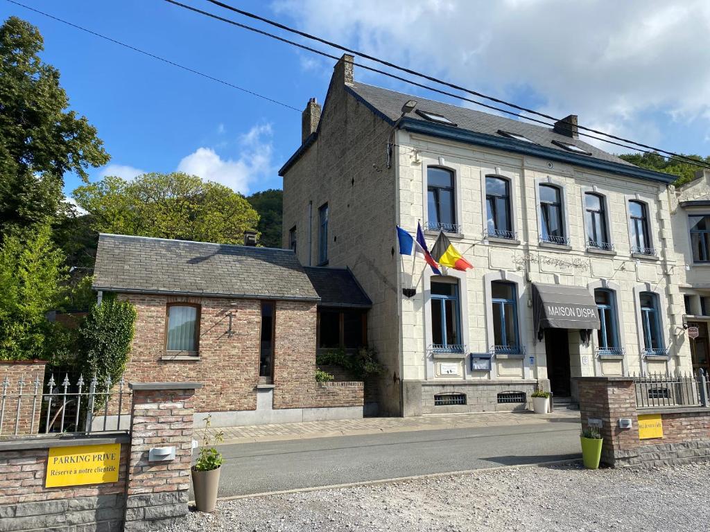 un vieux bâtiment en briques avec drapeaux dans une rue dans l'établissement Maison Dispa, à Walcourt