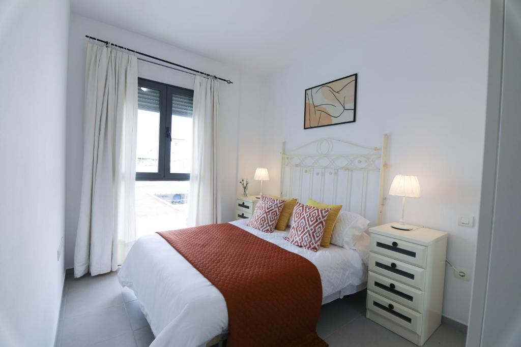Habitación blanca con cama y ventana en RentalSevilla Apartamento luminoso 2 dormitorios, en Sevilla