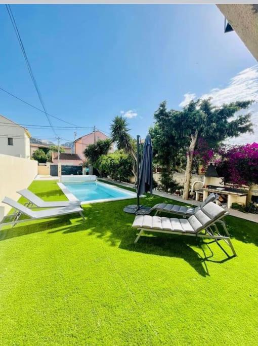 une pelouse avec deux chaises, un parasol et une piscine dans l'établissement A deux pas de la Mer, à Marseille