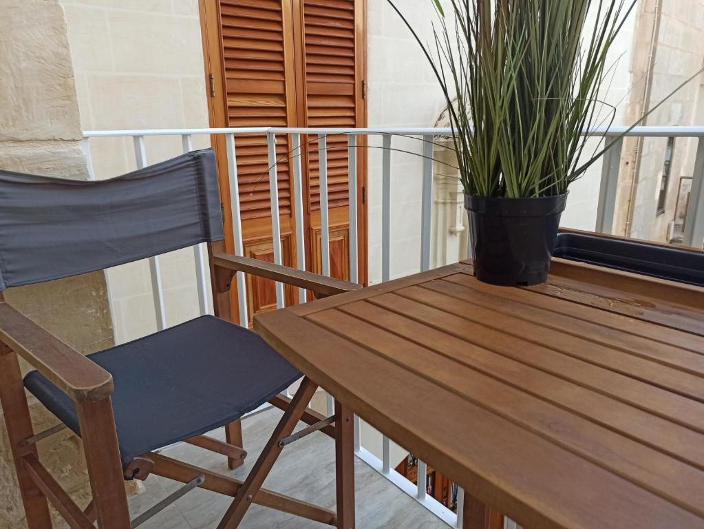 een houten tafel, een stoel en een potplant bij Beautiful Studio apartment in Qormi Malta in Qormi