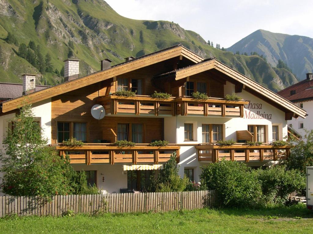 a building with a fence in front of a mountain at Apartment Madlaina in Samnaun