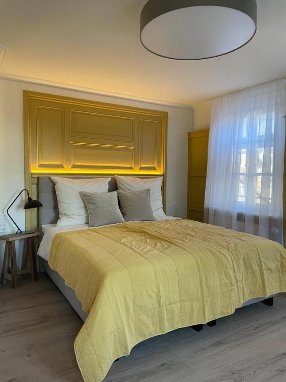 a bedroom with a large bed with a yellow blanket at Altes Rathaus in Schwaigern