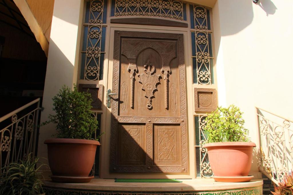 uma porta de madeira num edifício com dois vasos de plantas em luxury villa em Agadir