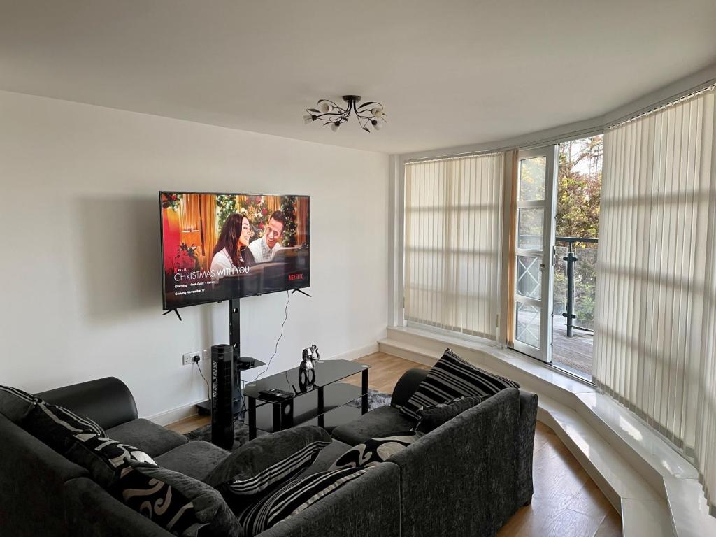 a living room with a couch and a flat screen tv at King Dems Home in Dagenham