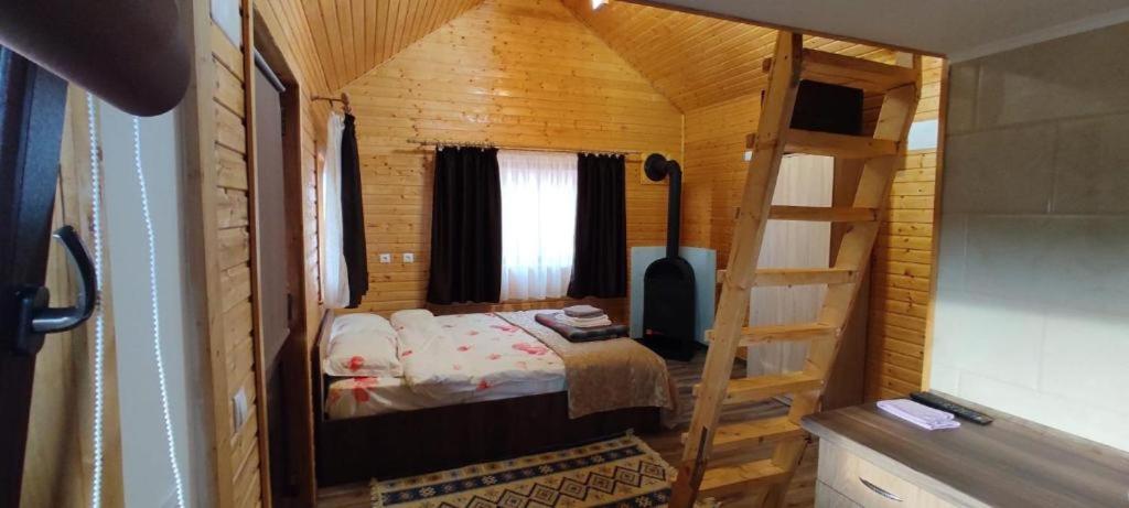 a small bedroom with a bed in a wooden cabin at La Hacienda in Cheţani