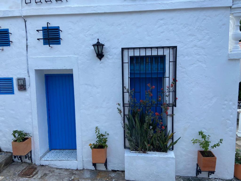 a white building with a blue door and some plants at Cabaña 12 La Tinaja Doradal Antioquia in Puerto Triunfo