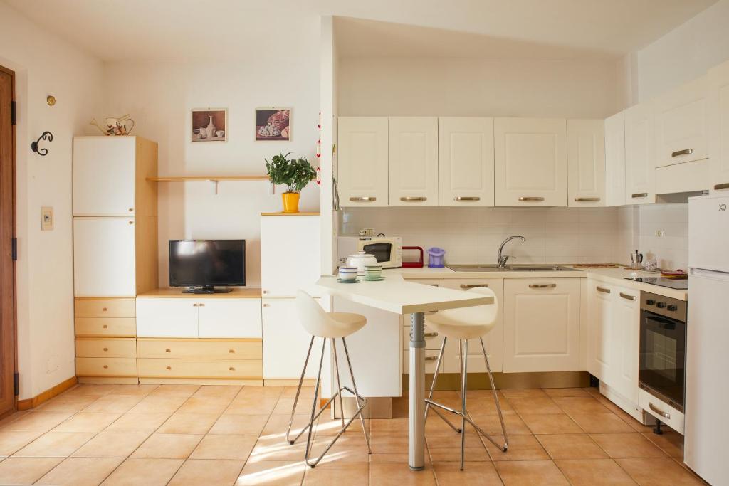 a kitchen with white cabinets and a table and stools at Conero - Patio Privato e Parcheggio by Host Hero in Marcelli