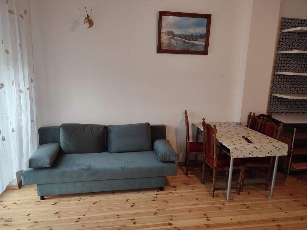 a living room with a blue couch and a table at Łapu Capu - Mieszkanie dla 4 osób in Grajewo