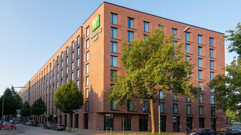 ein rotes Backsteingebäude mit einem grünen Schild darauf in der Unterkunft Holiday Inn - Hamburg - Berliner Tor, an IHG Hotel in Hamburg