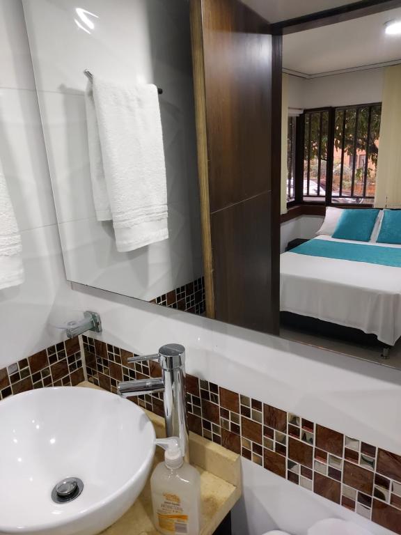 baño con lavabo, espejo y cama en Apartaestudio Laureles - Viva Laureles, en Medellín