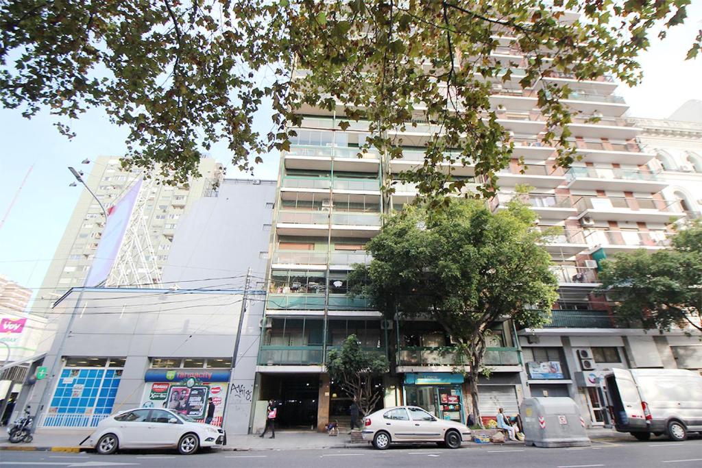 un edificio alto con coches estacionados frente a él en Habitación Verde en Buenos Aires