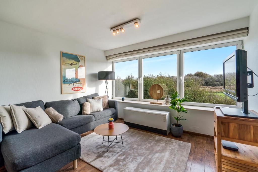 a living room with a couch and a large window at Duinenhuisje in Ostend