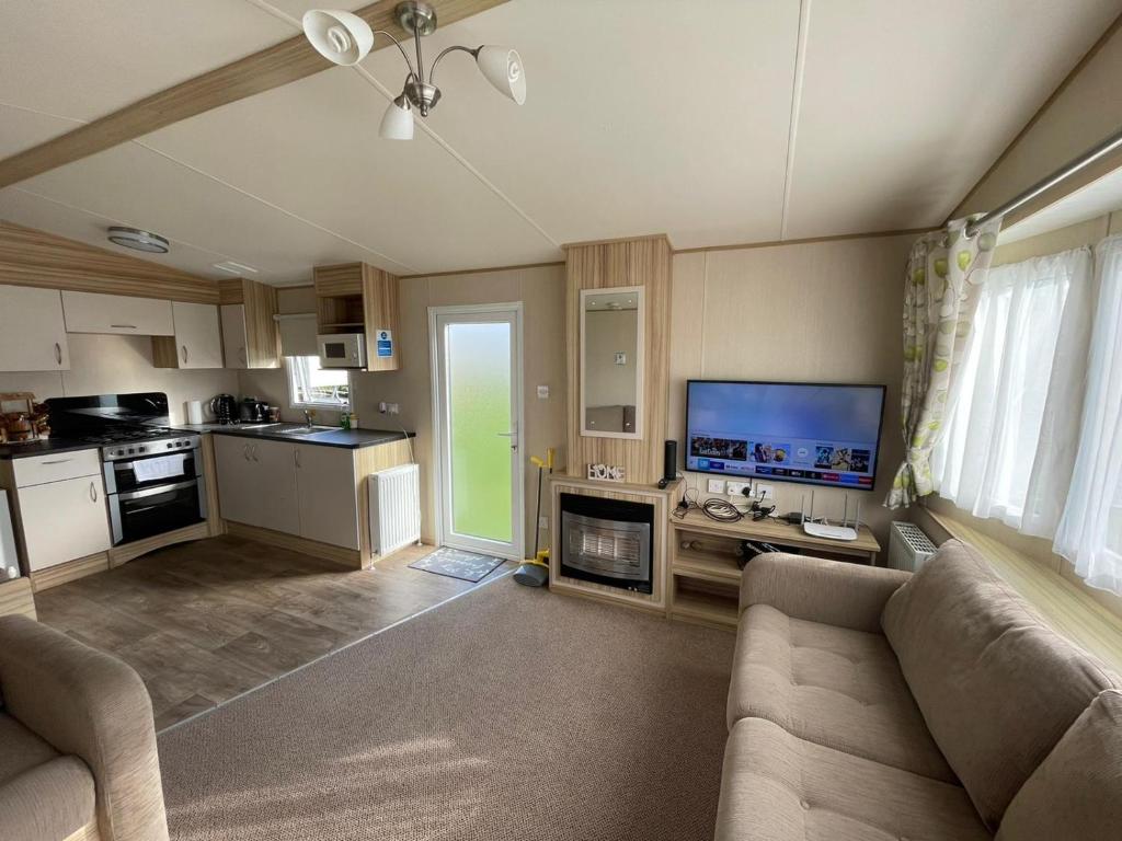 a living room with a couch and a kitchen at Fluffy Caravan Sleeps 4 Pet-Friendly in Leysdown-on-Sea
