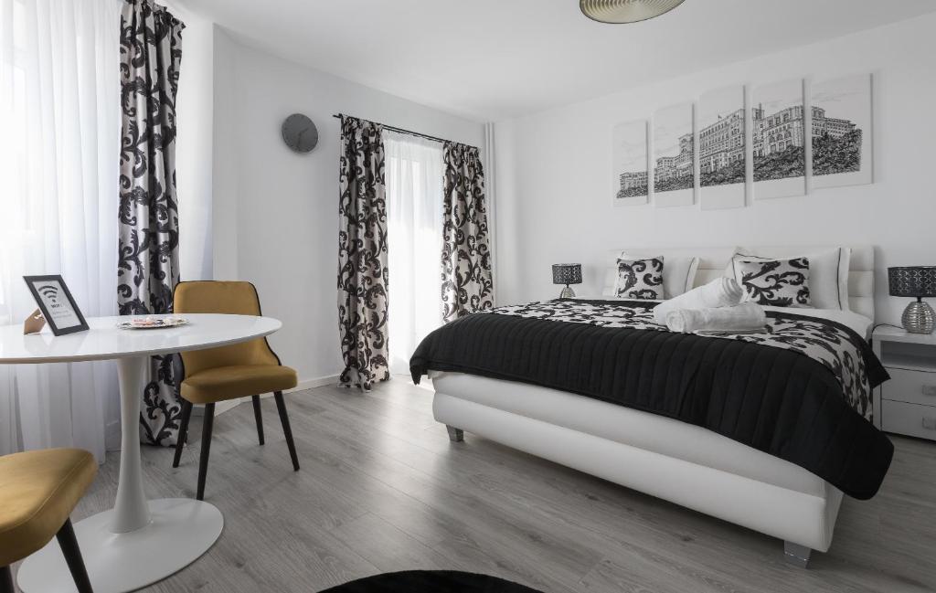 a white bedroom with a bed and a table at Lion's Unirii Apartment in Bucharest