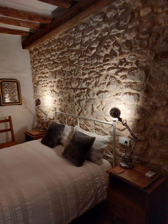 1 dormitorio con cama y pared de piedra en Casa de Pueblo Encantadora en San Jordi, Castellon, en Sant Jordi