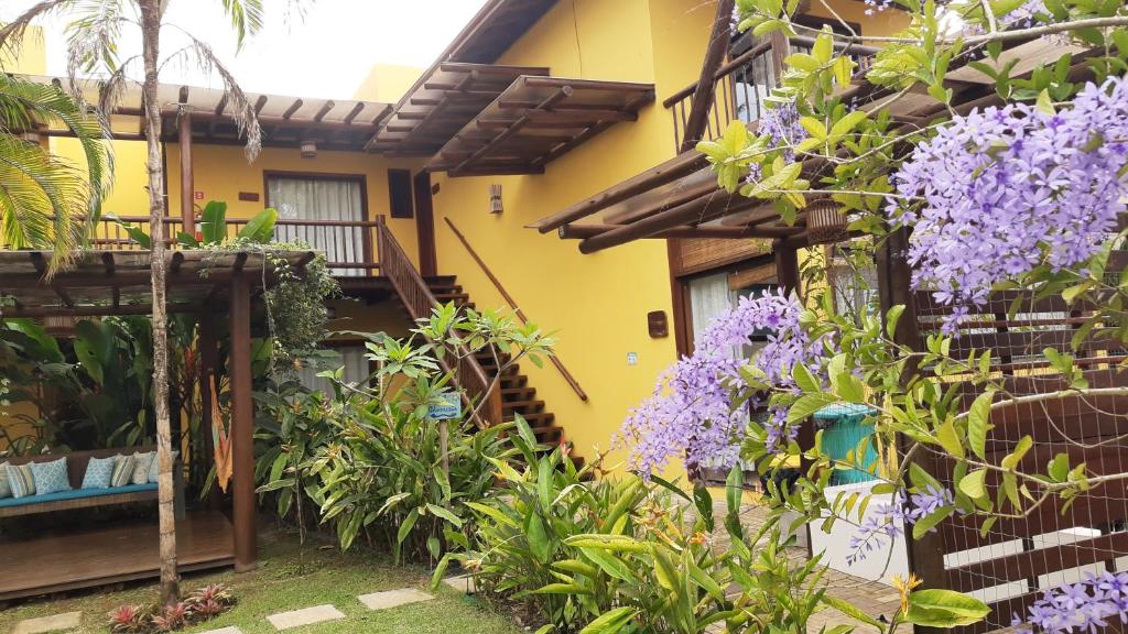 un jardin en face d'une maison ornée de fleurs violettes dans l'établissement Conchas do Mar Residence, à Itacaré