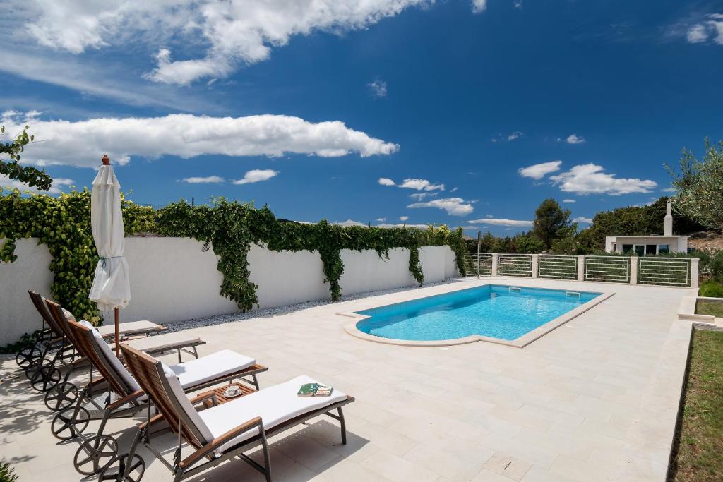 eine Terrasse mit einem Pool, 2 Stühlen und einem Sonnenschirm in der Unterkunft Villa Lilin San in Donji Humac