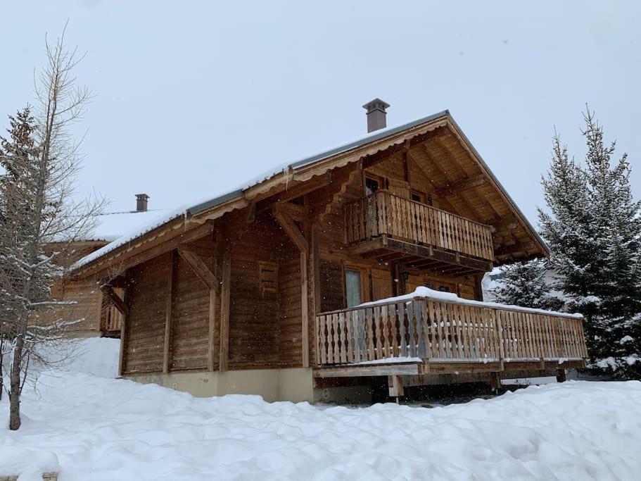 a log cabin with a deck in the snow at Chalet savoyard indépendant in La Toussuire