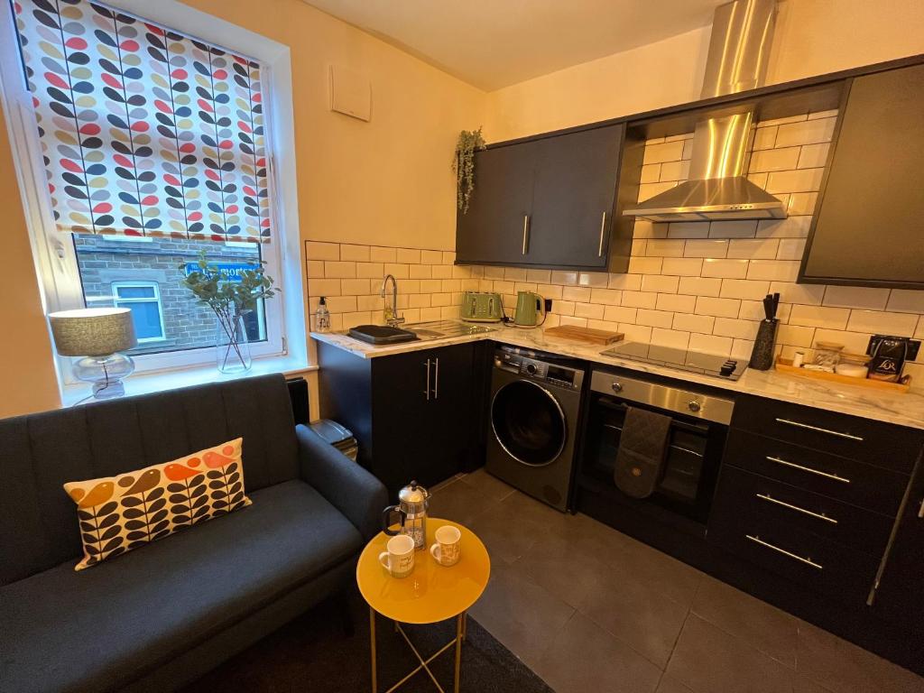 a small kitchen with a blue couch and a table at Modern & retro two bedroom apartment in Barnsley in Barnsley