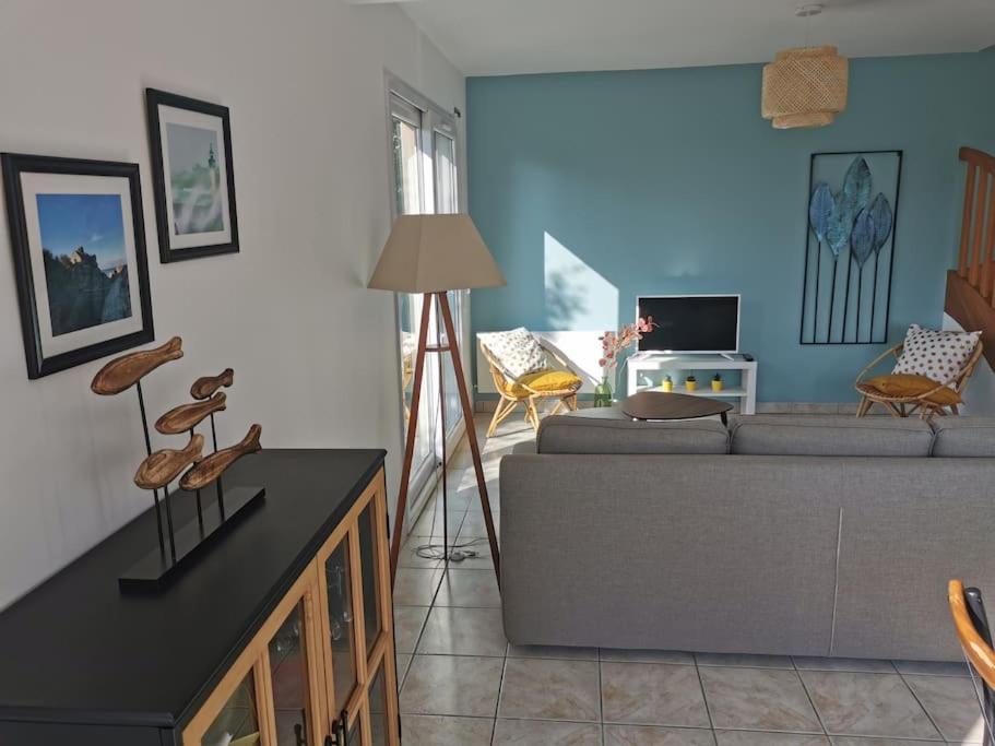 uma sala de estar com um sofá e uma mesa em Maison de vacances proche des plages et du GR34 em Sibiril