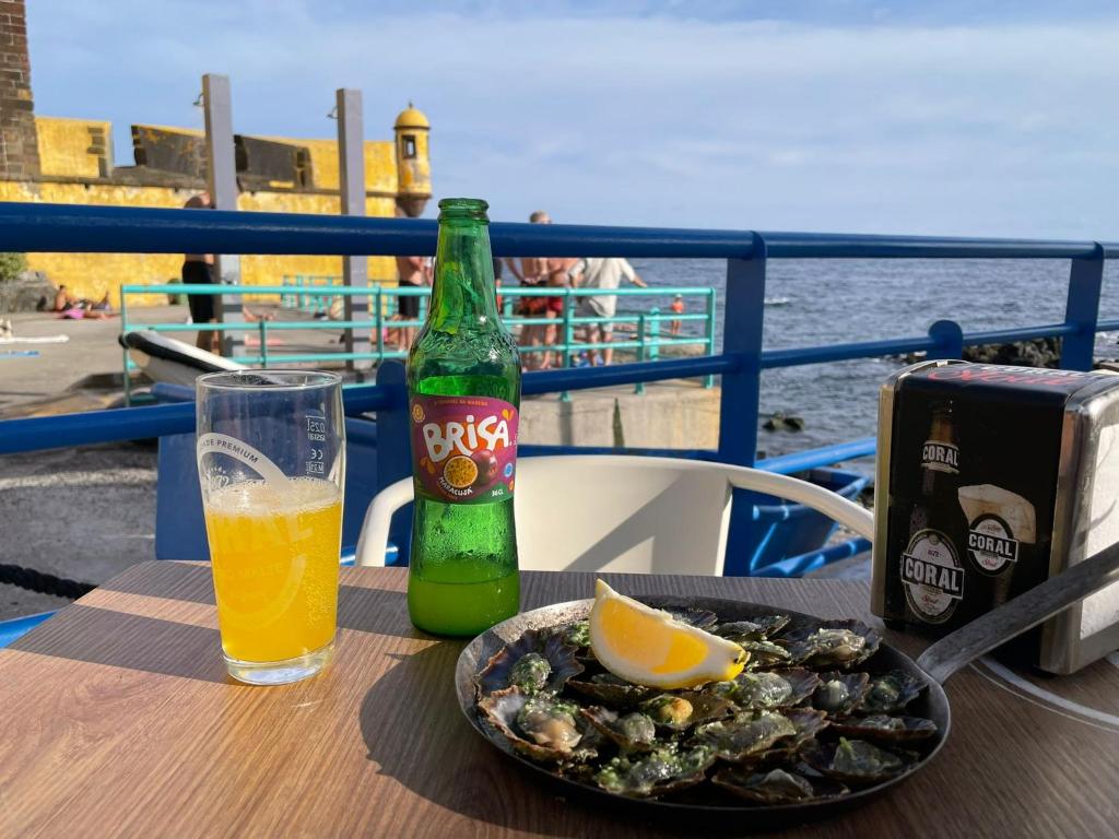 a table with a bottle of beer and a plate of food at Funchal Old Town Studios - Historic Atlantic View in Funchal