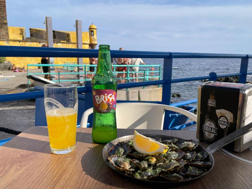 Una mesa con una botella de cerveza y un plato de comida. en Funchal Old Town Studios - Historic Atlantic View, en Funchal