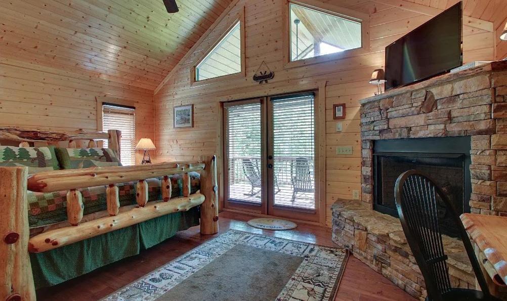 a log cabin bedroom with a fireplace and a tv at Astounding River View in Copperhill