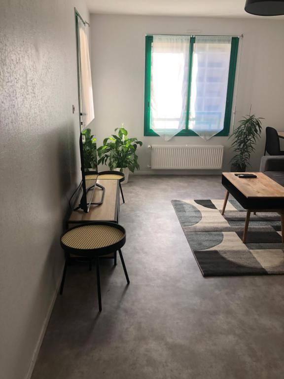 salon ze stołem i krzesłami oraz oknem w obiekcie Superbe Appartement en plein centre ville. w mieście La Roche-sur-Yon