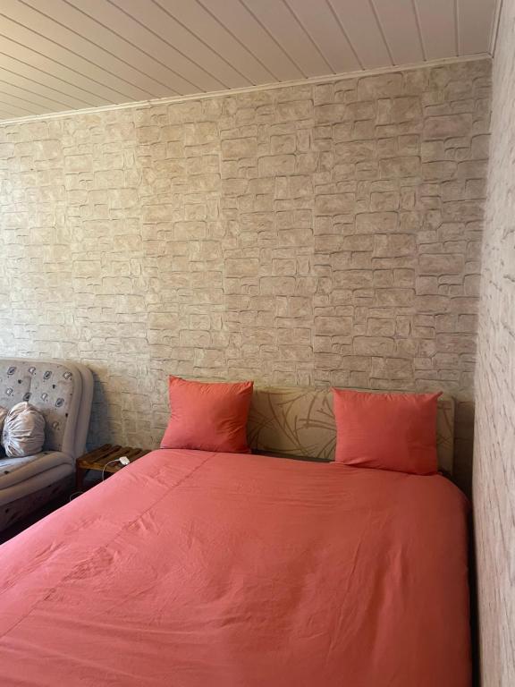 ein Bett mit zwei roten Kissen und einer Ziegelwand in der Unterkunft Airport Sarajevo Apartment 2 in Sarajevo