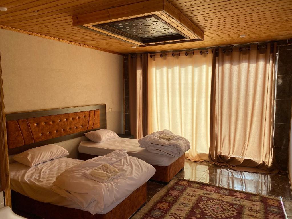 two twin beds in a room with a window at Desert Jewel Camp in Wadi Rum