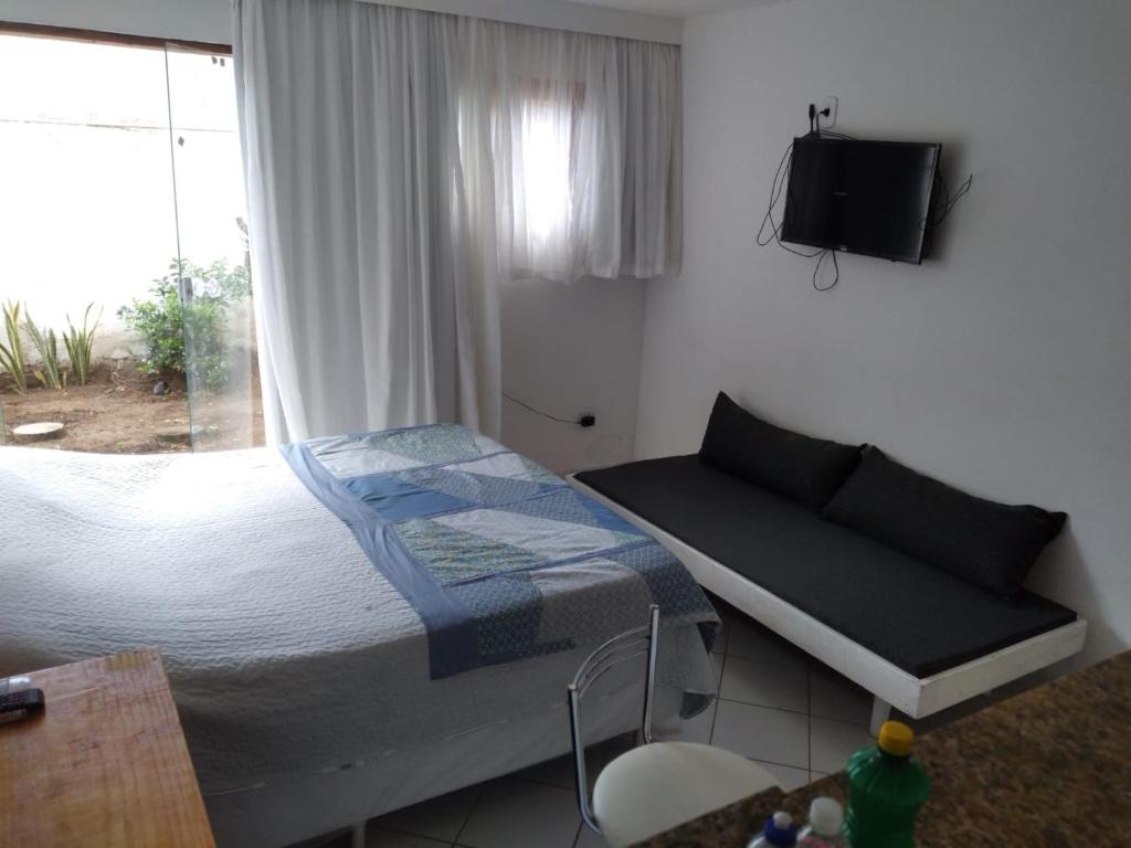 um quarto com uma cama, uma televisão e uma janela em Temporada Ilheus na Praia dos Milionarios Kitnet em Ilhéus
