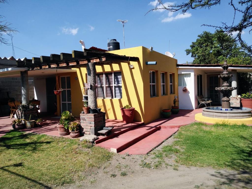 une maison jaune avec pergola sur une cour dans l'établissement Finca Mc'Clau Teotihuacan, Casa residencial entera, à San Martín de las Pirámides